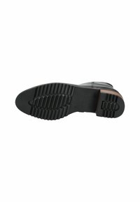 Suela de bota de cuero negro con una superficie texturizada, que presenta ranuras horizontales y verticales para tracción y un ligero acento de madera en el tacón.