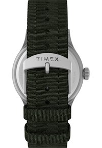 Reloj Timex con correa de tela verde oscuro, caja de acero inoxidable, forma redonda y herrajes plateados. Resistente al agua hasta 50 metros.