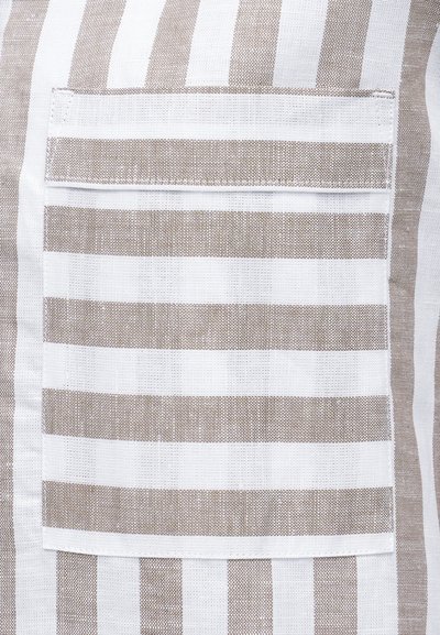 Κοντινή λήψη τσέπης από μπεζ και λευκό ύφασμα με οριζόντιες ρίγες ραμμένη σε φόντο με κάθετες ρίγες ύφασμα.