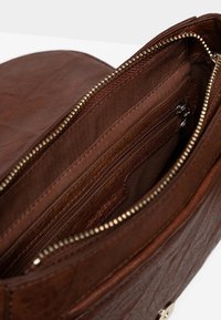 Borsa in pelle marrone aperta per mostrare la fodera interna in tessuto, tasca con zip e dettagli della zip color oro.