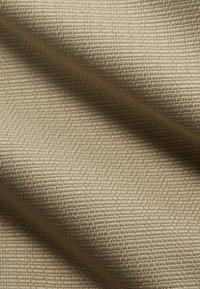Tejido texturizado beige que muestra un patrón tejido con una apariencia similar a una cuadrícula, enfatizando su estructura suave y duradera y su color neutro.