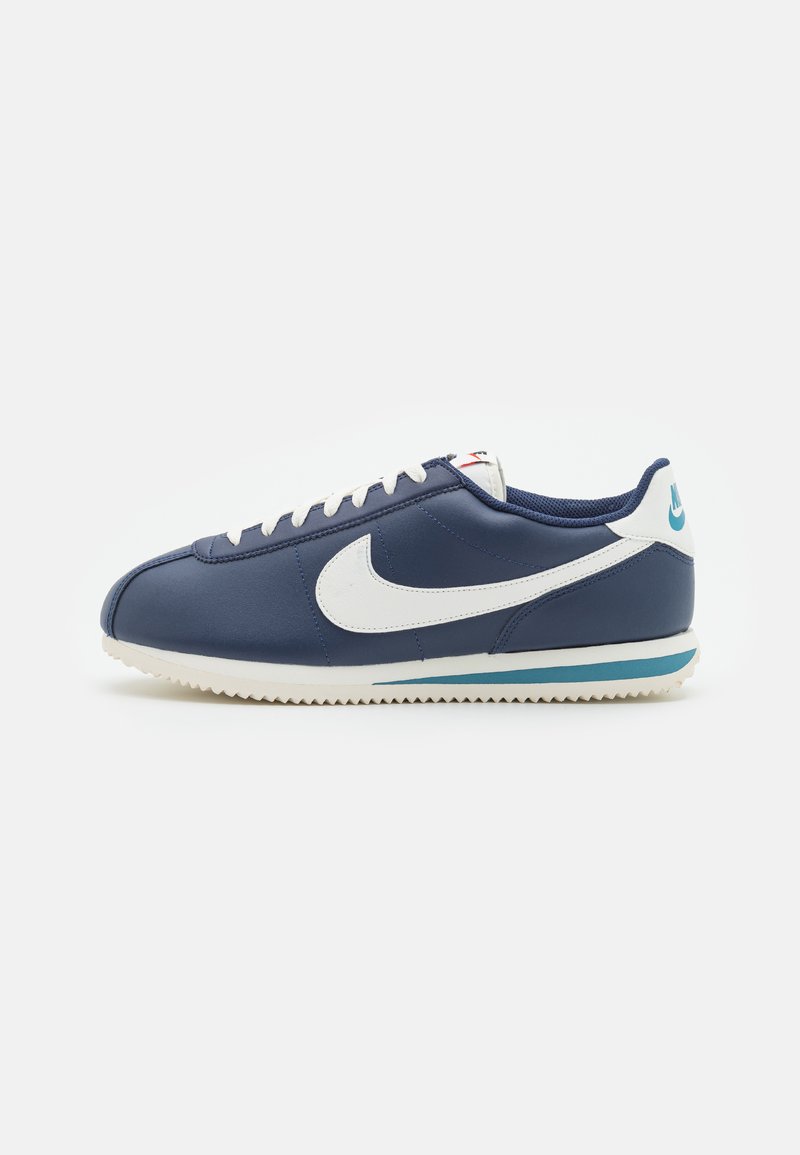 Nike sneakers with navy blue synthetic upper, white accents, lace closure, and a patterned rubber outsole. Features a blue trim at the sole.