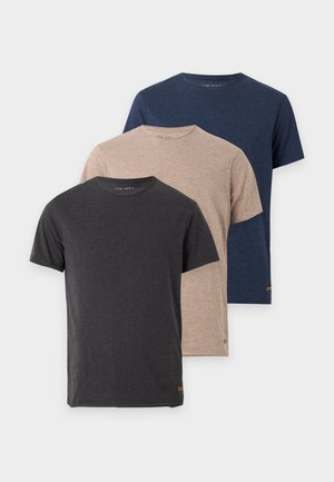 Homme portant un t-shirt gris foncé, un short gris clair, des chaussettes blanches et des baskets blanches, debout devant un fond blanc uni.