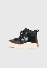 Zapatilla alta negra con parte superior de cuero brillante, acentos texturizados y una suela de goma blanca con una franja de marca roja.