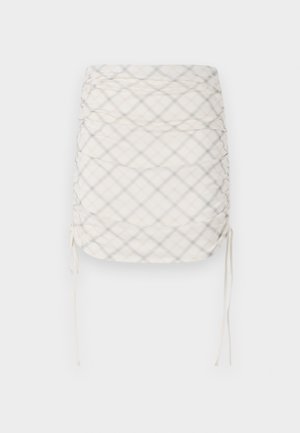Ruched mini skirt in cream with gray and beige plaid pattern. Features adjustable side ties and a smooth, textured fabric.
