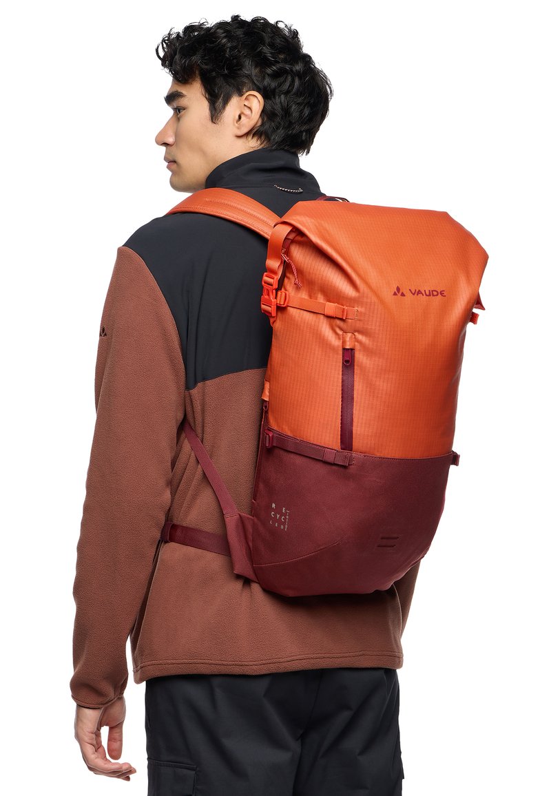 Mochila VAUDE en naranja y marrón, con un diseño de parte superior enrollable, correas ajustables, tela texturizada y un bolsillo frontal con cierre de cremallera.