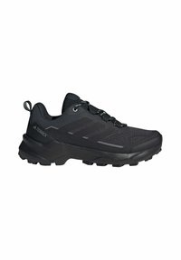 Scarpa da trekking Adidas Terrex nera con suola robusta, tomaia in mesh, chiusura con lacci e linguetta sul tallone per uso outdoor.