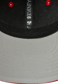 Grauer Hut mit flachem Schirm, schwarzer Unterseite und roten Akzenten. Verfügt über einen strukturierten Stoff und sichtbare Nähdetails. 9SEVENTY-Label enthalten.