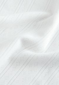 Bijela teksturirana tkanina s uzdignutim uzorcima i dijagonalnim linijama. Mekano pada, lagana je i upletena s složenim geometrijskim detaljima.