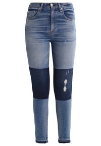 Jeans de mezclilla de patchwork que muestran tonos variados de azul y oscuro índigo; presentan un acabado desgastado y un diseño de corte slim.