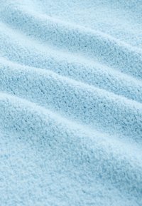 Hele sinine tekstureeritud kangas, millel on pehme ja sametine tunne, ebaühtlased lained ja karvane pind, mis viitab hubasele ja sooja materjalile.