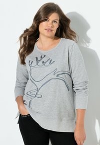Sudadera gris de manga larga, con un diseño de dibujo en línea negra en la parte frontal. Confeccionada en material suave, corte relajado y aberturas laterales en el dobladillo.