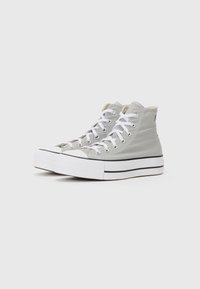 High-top sneakers in light grey canvas with white laces, rubber toe cap, and black accents along the sole. Simplistic design and texture.