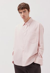 Helles rosa, langärmliges Hemd mit weißen vertikalen Streifen, Button-Down-Kragen, einer Brusttasche und lockerer Passform. Glatte Stoffstruktur.