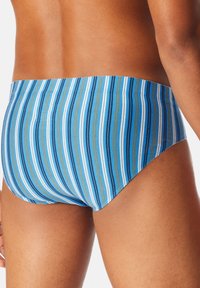 Zwemslips met horizontale strepen in blauw, wit en bruin, gemaakt van rekbare stof. Het ontwerp heeft een hoge taille en een strakke pasvorm.