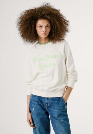 Sweatshirt léger crème avec "Pepe Jeans London" en vert. Caractéristiques : encolure ronde avec une bordure verte et manches raglan. Porté avec un jean bleu.