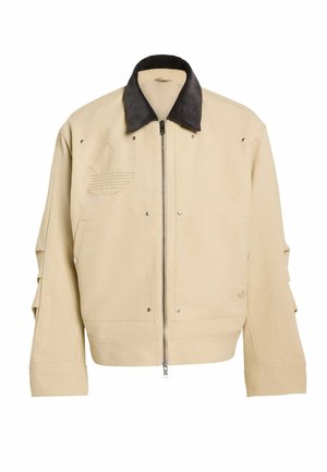 Béžová bomber bunda s černým manšestrovým límcem, zapínáním na zip, bočními kapsami a vyšívaným logem. Texturovaná l�átka se stříbrnými cvočky.
