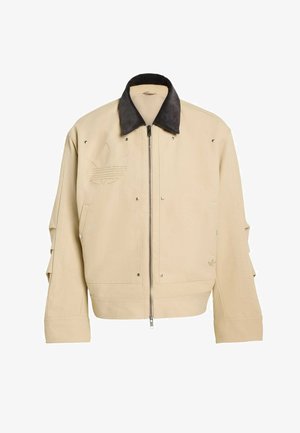 Beige bomberjack met een zwarte corduroy kraag, ritssluiting, zijzakken en een geborduurd logo. Gestructureerde stof met zilveren studs.