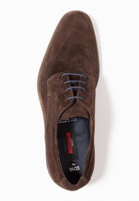 Chaussure en daim marron avec des lacets bleus, bout arrondi et un design cousu. Dotée d'une semelle intérieure en cuir et d'une semelle extérieure en caoutchouc pour une meilleure adhérence.
