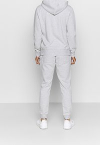 Grau Hoodie und Jogginghose Set aus weichem Material. Hoodie mit Kordelzug und Kängurutasche; Hose hat einen elastischen Bund und Bündchen.