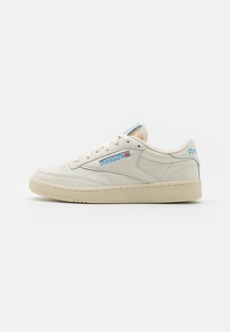 Baskets Reebok en cuir crème avec des accents bleu clair, dotées d'un col rembourré, d'un design à lacets et d'une semelle en caoutchouc texturée.
