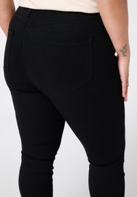 Zwarte denim jeans met een gladde, rekbare afwerking. Ze hebben een klassiek vijf-pocket ontwerp met twee achterzakken van stof.