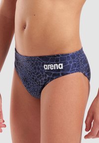 Marine svømmedragt med en struktureret blå-sorte dyreprint, der har et hvidt "arena" logo på taljen. Glat, strækbart stof.
