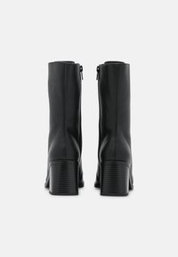 Czarne skórzane botki na kostkę z zamkiem błyskawicznym, z żeberkowanym obcasem typu blok i gładką powierzchnią, zaprojektowane dla dopasowanej sylwetki.