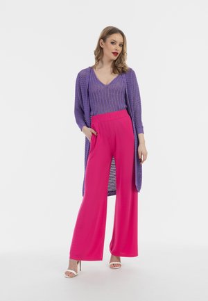 Violetti neulecardigan vaaleanpunaisen leveälahkeisen housun ja istuvan violettitopin päällä. Asusteessa on teksturoitu kuvio ja valuva muotoilu.
