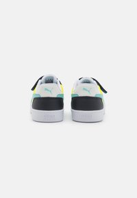 Witte en zwarte sneakers met gele en aqua accenten, met een gladde leren afwerking en een merkachtige hieltab. De achterkant toont een instapontwerp.