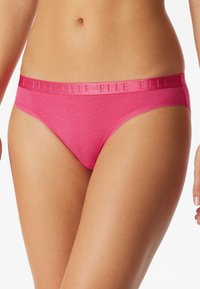 Růžové bavlněné bikiny spodní prádlo s hladkou texturou, s lesklým páskem s vyraženým názvem značky. Jednoduchý, čistý design.