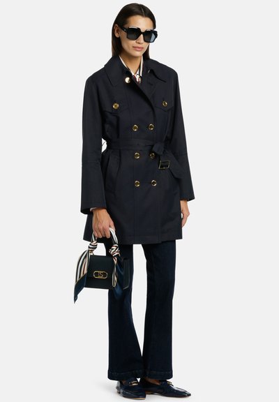 Jūras spēku garais mētelis ar zeltītām pogām, jostotu vidukli un izslēgtām piedurknēm. Apvienots ar tumšiem džinsiem un mazu rokassomu, kas rotāta ar dekoratīvu šalli.