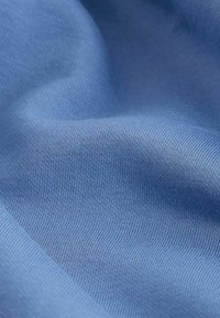 Lyseblåt stof med en glat, let struktureret overflade og et fint, ensartet ribbet mønster gennem hele stoffet.