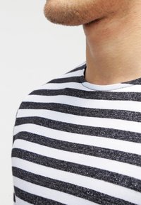 Katoenen T-shirt met een ronde hals, voorzien van horizontale zwart-witte strepen, een gladde textuur en een licht gemêleerd uiterlijk op de zwarte strepen.