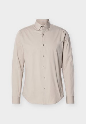 Camisa de manga larga en algodón beige claro. Presenta un cuello puntiagudo y una tapeta frontal con botones a juego. Textura suave.