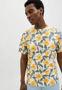 Tricou cu mânecă scurtă, decorat cu un model floral cu flori galbene și frunze verzi pe un fundal alb. Material din bumbac moale și ușor.