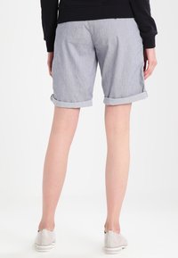 Shorts gris à revers fabriqués dans un tissu léger, avec une texture subtile, taille mi-haute et coupe décontractée.