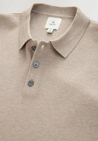 Beige kortærmet polo shirt med tre mørke knapper og krave, mærket størrelse medium, fremstillet i Myanmar.
