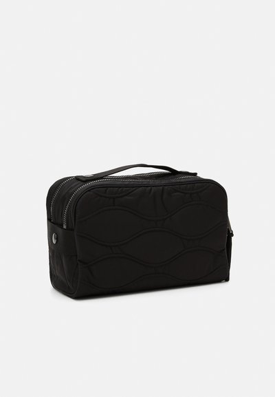 Geantă cosmetică neagră, matlasată, cu formă dreptunghiulară, cu închidere prin fermoar, mânere de transport și model in valuri pe suprafață. Fabricată din material durabil.