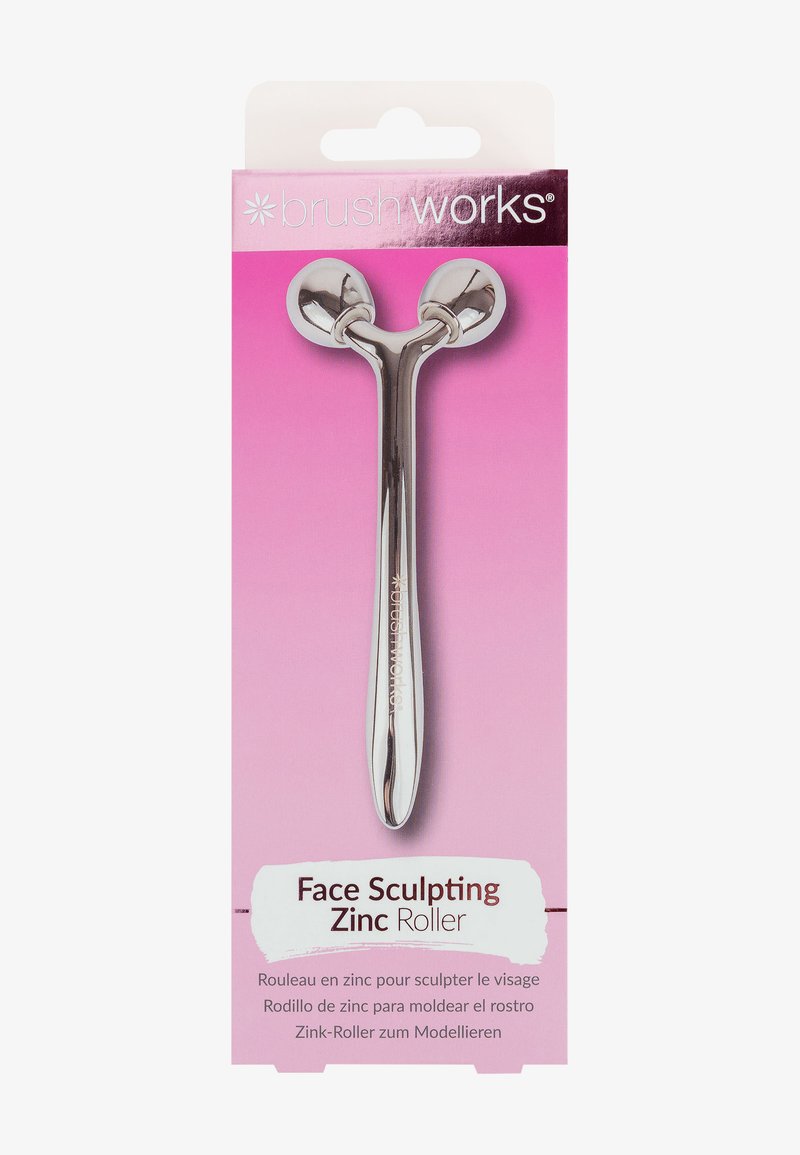 Sinkeface roller med glitrende sølvfinish, med to runde ender, montert på et slankt håndtak. Pakket mot en rosa bakgrunn.