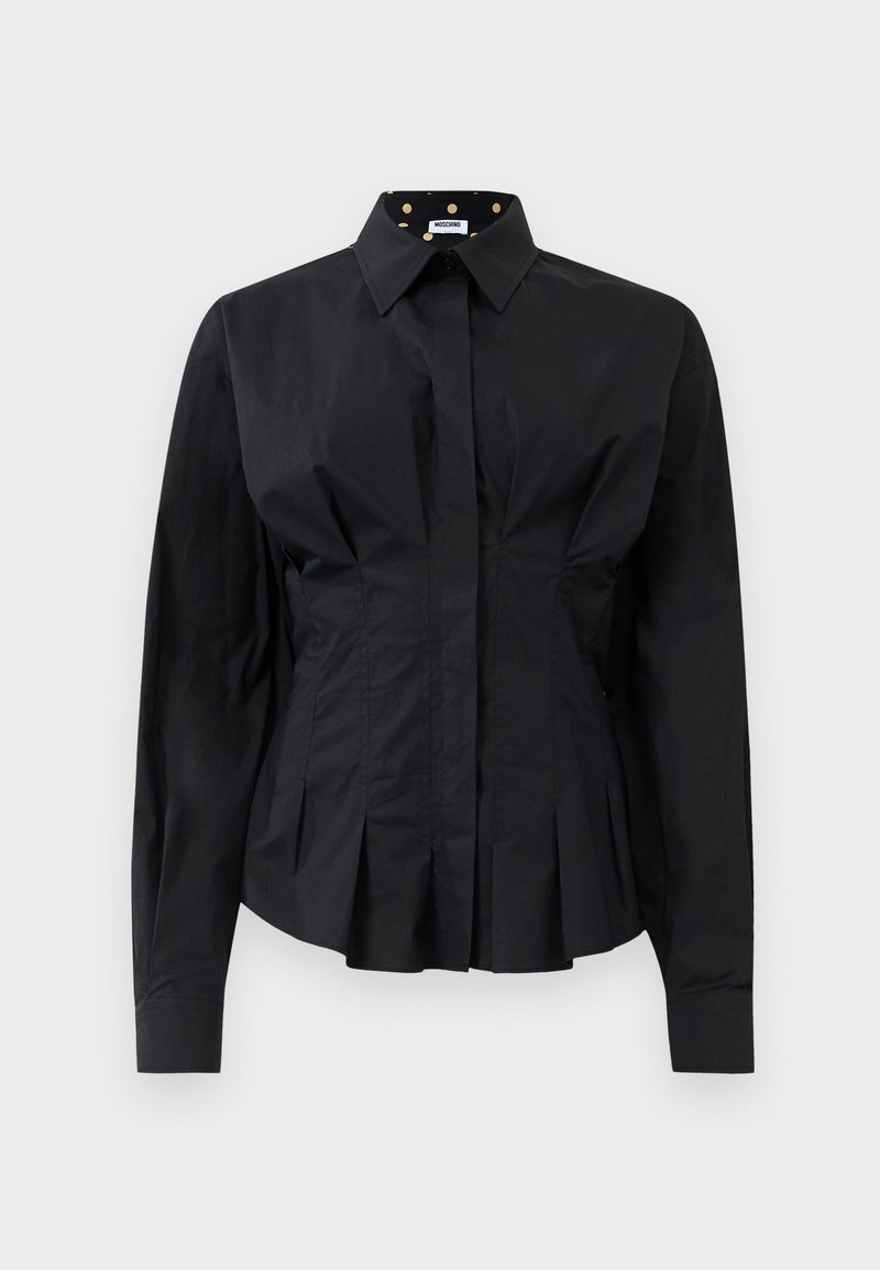 Zwarte fitted lange mouwen shirt met gestructureerde plooien onder de taille en een kraag gevoerd met gouden stippen op zwarte stof.