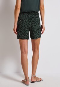Zelené šortky s černým leopardím vzorem. Vyrobené z lehkého materiálu, s pohodlným pasem a ohrnutými lemy.