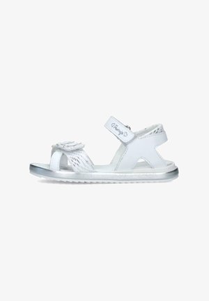 Sandalo bianco in materiale sintetico, con fascetta regolabile in velcro, accentuato da fiori e rifiniture argento. Presenta un design aperto e una soletta testurizzata.