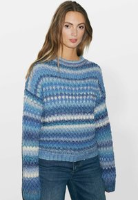 Sinine kootud sviiter, millel on erinevad triibud helesinistes ja tumesinistes toonides. Ribiga kaelus ja mansetid, lauge istuvuse disain.