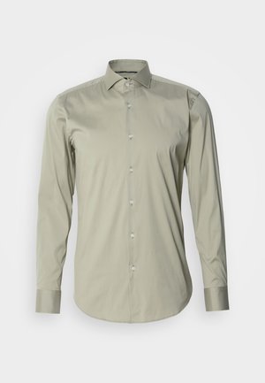Langermet skjorte i lys olivenfarge, laget av glatt stoff. Har spiss krage, knappestolpe foran og mansjetter med knappdetaljer.