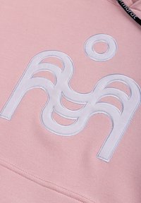 Jasnoróżowa bluza z kapturem z wyróżniającym się białym haftowanym logo z abstrakcyjnymi kształtami i zaokrąglonymi akcentami z przodu.