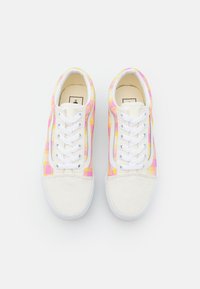 Baskets à lacets en toile blanche avec des accents à carreaux jaunes et roses sur les côtés et un embout texturé blanc.