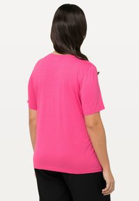 T-shirt a maniche corte di colore rosa brillante, realizzato in tessuto morbido. Presenta un collo rotondo e una vestibilità rilassata, con dettagli di cucitura minimi sull'orlo.
