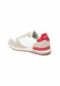 Sneaker con una toma in pelle bianca, accenti in suede beige, linguetta rossa sul tallone e suola in gomma testurizzata. Presenta una finitura liscia e chiusura con lacci.