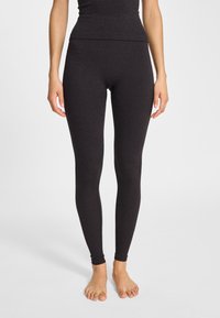 Czarne legginsy wykonane z miękkiego, rozciągliwego materiału, z wysokim stanem i dopasowanym krojem, sięgające do kostek bez widocznych szwów.